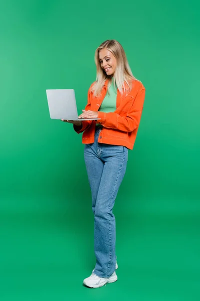 Volledige Weergave Van Lachende Vrouw Oranje Jas Jeans Met Laptop — Stockfoto