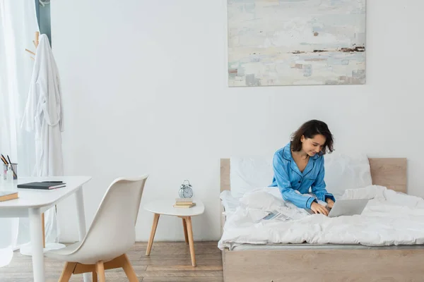 Alegre Joven Mujer Pijama Usando Portátil Cerca Periódico Cama — Foto de Stock