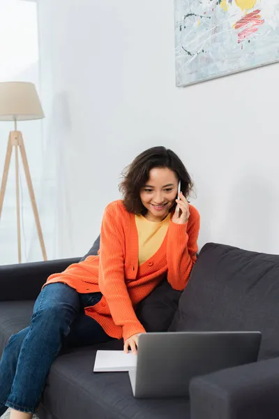 Glad Ung Kvinna Pratar Mobilen Och Använder Laptop Soffan — Stockfoto