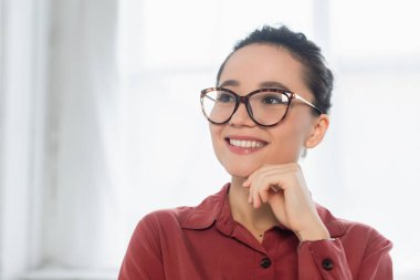 Gözlüklü mutlu genç öğretmen başka tarafa bakıyor.