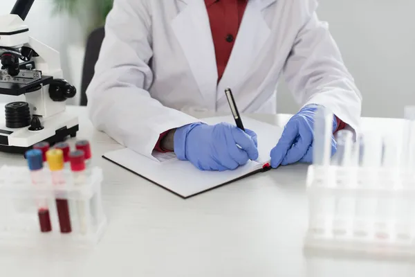 Vista Recortada Del Científico Guantes Látex Escrito Cuaderno Cerca Tubos — Foto de Stock