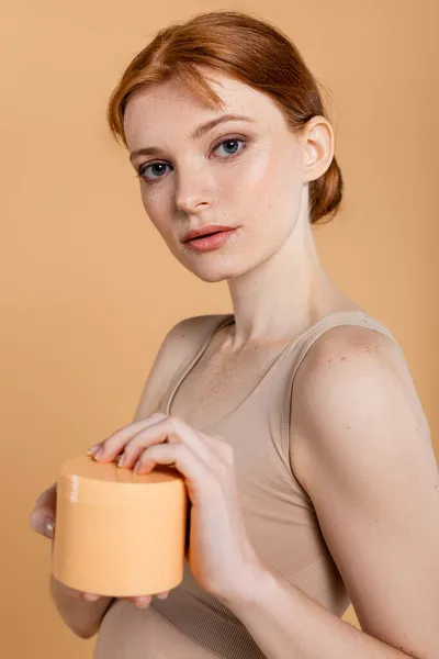 Retrato Jovem Mulher Sardenta Segurando Creme Cosmético Isolado Bege — Fotografia de Stock