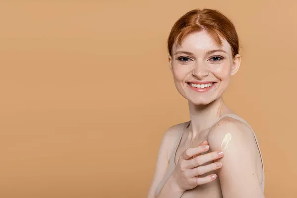 Donna Rossa Positiva Che Applica Crema Cosmetica Guarda Fotocamera Isolata — Foto Stock