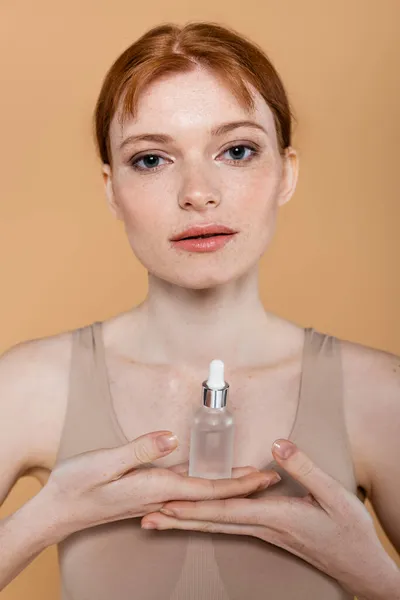 Jonge Roodharige Vrouw Met Cosmetisch Serum Kijken Naar Camera Geïsoleerd — Stockfoto