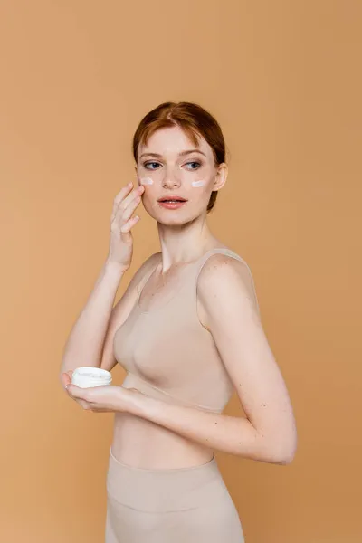 Young Woman Top Applying Cosmetic Cream Cheeks Isolated Beige — Stock Photo, Image