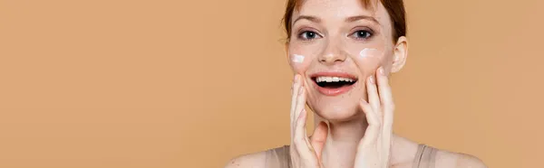 Excited Freckled Woman Cosmetic Cream Cheeks Looking Camera Isolated Beige — Stock Photo, Image