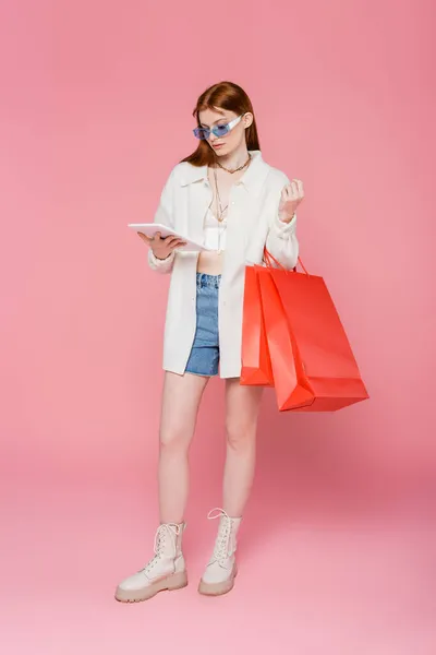Stílusos Vörös Hajú Kezében Digitális Tabletta Bevásárló Táskák Rózsaszín Alapon — Stock Fotó