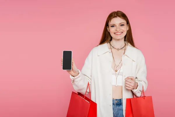 Söt Rödhårig Kvinna Med Shoppingväskor Som Håller Mobiltelefon Med Blank — Stockfoto