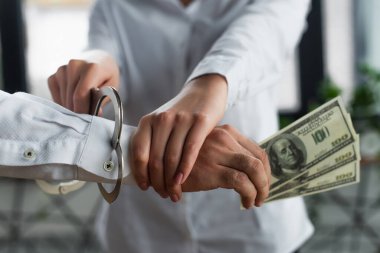 KYIV, UKRAINE - 22 Eylül 2021: Kadınlara kısmi bakış açısı: Erkeğe dolarla kelepçe takmak, yolsuzlukla mücadele kavramı