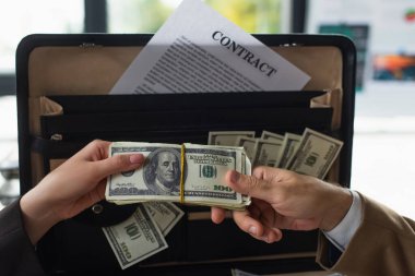 KYIV, UKRAINE - 22 Eylül 2021: Yolsuzlukla mücadele konsepti ile evrak çantasının yanında dolar tutan işadamları hakkında kırpılmış görüş