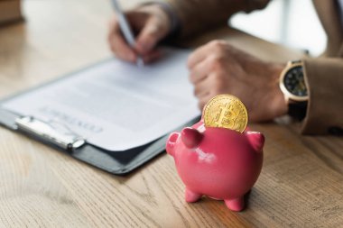 KYIV, UKRAINE - SEPTEMBER 22, 2021: Bitcoin, yolsuzlukla mücadele konsepti ile domuz kumbarasının yanında iş adamı sözleşmesi imzalanması görüşü
