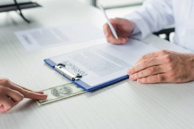 Doktorun dolarlar ve yolsuzlukla mücadele konsepti olan bir hastanın yanında kontrat imzalaması