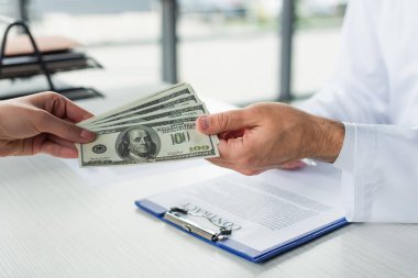 KYIV, UKRAINE - 22 EYLÜL 2021: Yolsuzlukla mücadele konseptine yakın doktorlara rüşvet veren kadına kısmi bakış