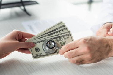 Steteskopu olan bir doktorun, dolar banknotları ve yolsuzlukla mücadele konsepti olan bir hastanın yanında ne işi var?