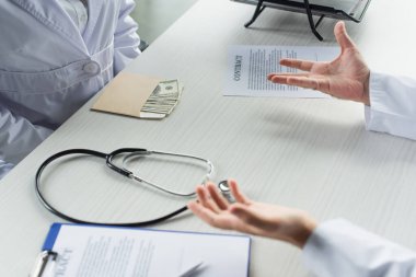 Zarfın içi dolarla dolu. Hasta ve doktor açık avuç içleri, yolsuzlukla mücadele kavramı.