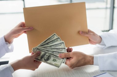 KYIV, UKRAINE - 22 Eylül 2021: Doktora zarf ve dolar veren hastanın kısmi görüşü, yolsuzlukla mücadele kavramı