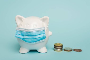 Mavi ve yolsuzlukla mücadele kavramının üzerinde altın ve gümüş sikkelerin yanında tıbbi maskede para kutusu