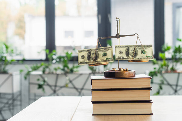 КИЕВ, УКРАИНА - 22 СЕНТЯБРЯ 2021 года: масштабы правосудия с долларовыми банкнотами на книгах в офисе, антикоррупционная концепция