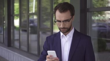 Takım elbiseli bir işadamı açık havada cep telefonu kullanıyor. 