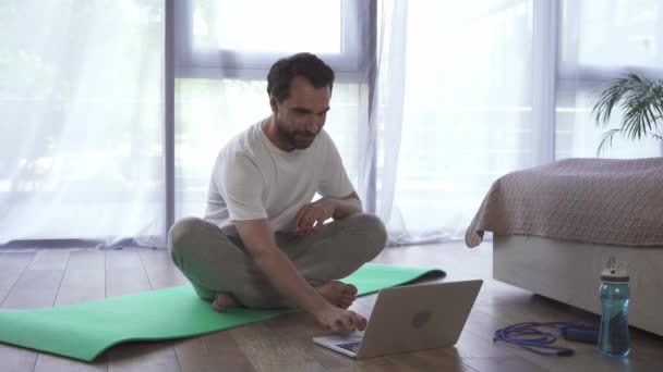 Άντρας Που Χρησιμοποιεί Φορητό Υπολογιστή Ενώ Διαλογίζεται Στρώμα Γυμναστικής Στο — Αρχείο Βίντεο