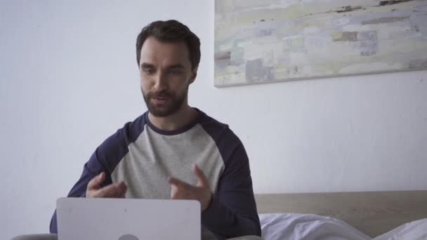 Mosolygós Férfi Gesztikulál Miközben Videó Hívás Laptop Hálószobában — Stock videók