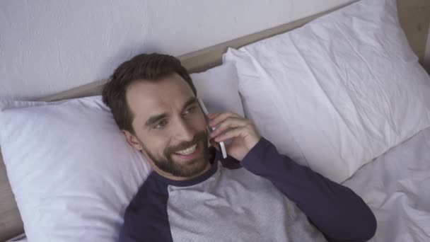 Bovenaanzicht Van Vrolijke Man Aan Het Praten Smartphone Bed — Stockvideo