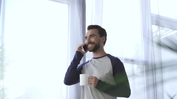 Sorrindo Homem Com Copo Falando Smartphone Casa — Vídeo de Stock