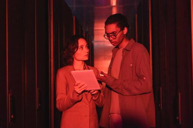 Afro-Amerikan mühendis veri merkezindeki meslektaşımın yakınındaki dijital tableti işaret ediyor.