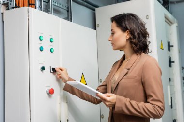 technician operating switchboard in data center while holding digital tablet clipart