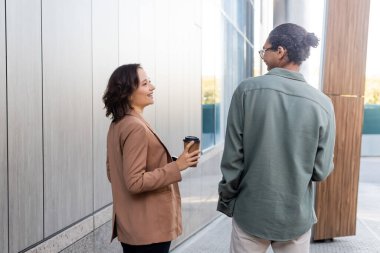 Afro-Amerikalı bir adamın, mutlu bir kadının yanında, şehir sokağında içkisini yudumlarken görüntüsü.