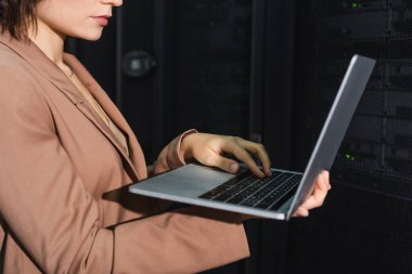 Veri merkezinde sunucuların yanında çalışırken dizüstü bilgisayar kullanan programcının kırpılmış görüntüsü