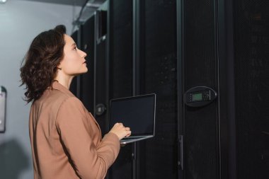Veri merkezinde sunucuya bakarken dizüstü bilgisayarı boş ekran ile tutan programcı