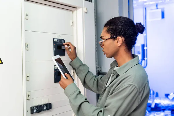 Joven Ingeniero Afroamericano Haciendo Diagnósticos Centralita Mientras Sostiene Tableta Digital — Foto de Stock