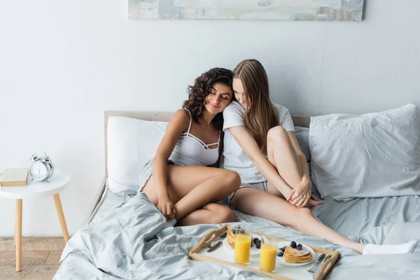 Glückliche Freundinnen Sitzen Auf Dem Bett Der Nähe Tablett Mit — Stockfoto