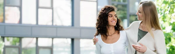 Smiling Young Woman Hugging Curly Girlfriend While Walking Banner — Stock Photo, Image