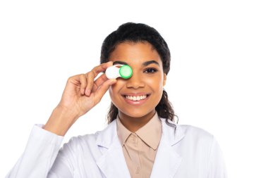Gülümseyen Afrikalı Amerikalı doktor, beyaz bir yüzün yakınında kontak lensleri tutuyor. 