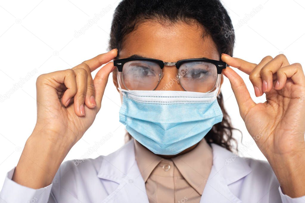 African american doctor in fogged eyeglasses and medical mask looking at camera isolated on white 