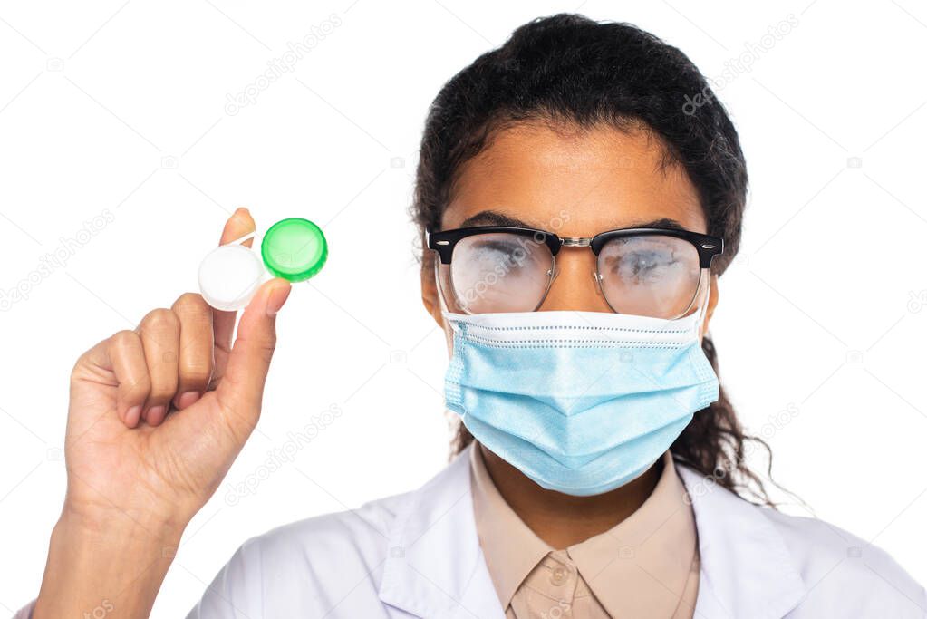 African american doctor in fogged eyeglasses and medical mask holding contact lenses isolated on white 