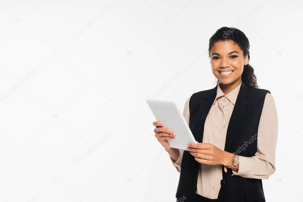 Smiling african american businesswoman in vest holding digital tablet isolated on white 