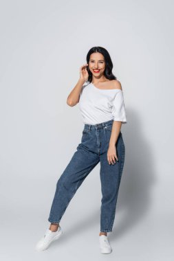 Gülümseme ve moda kadının gri üzerinde dururken saç düzeltme görüntüsü