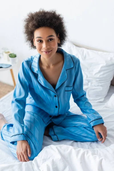 穿着睡衣坐在床上的积极而年轻的非洲裔美国妇女的高视角 — 图库照片