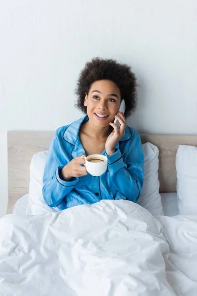 Smiling African American Woman Pajamas Talking Smartphone Holding Cup Coffee — Stock Photo, Image