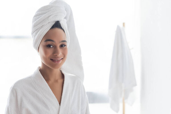cheerful african american woman in white towel looking at camera