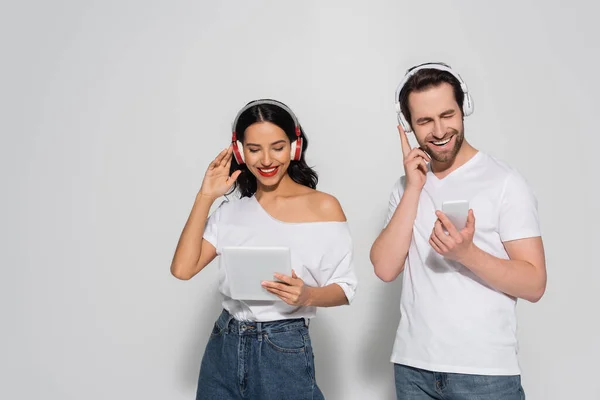 Alegre Pareja Con Gadgets Ajustando Auriculares Mientras Escucha Música Gris —  Fotos de Stock