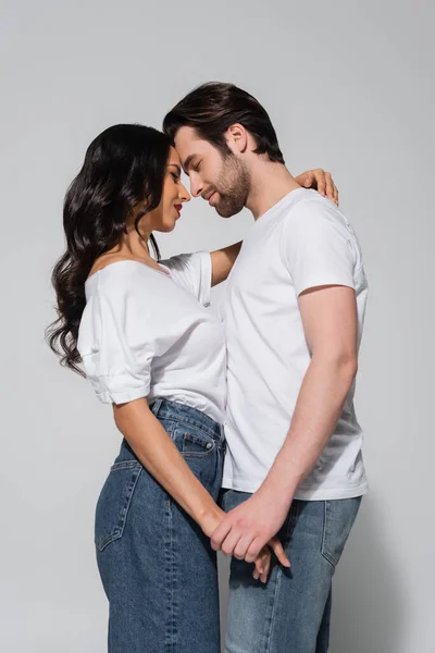 灰色の顔をしながら手を取り合っているカジュアルな服を着た若いカップルの側面図 — ストック写真