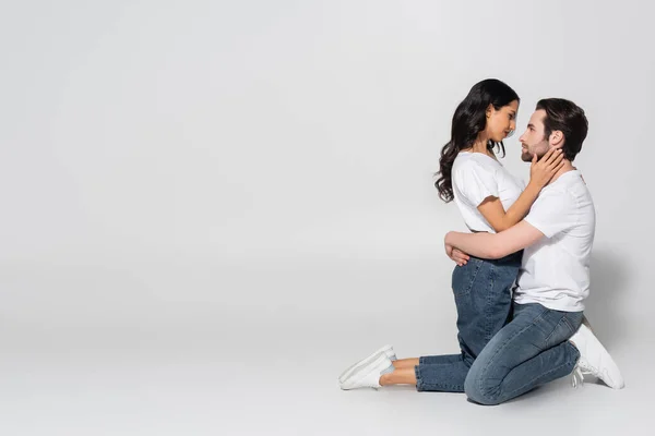 Vista Lateral Casal Camisetas Brancas Jeans Sobre Joelhos Abraçando Cinza — Fotografia de Stock