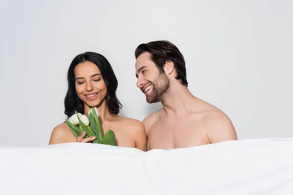 Smiling Sensual Woman Holding Tulips Shirtless Man White Blanket Isolated — Stockfoto