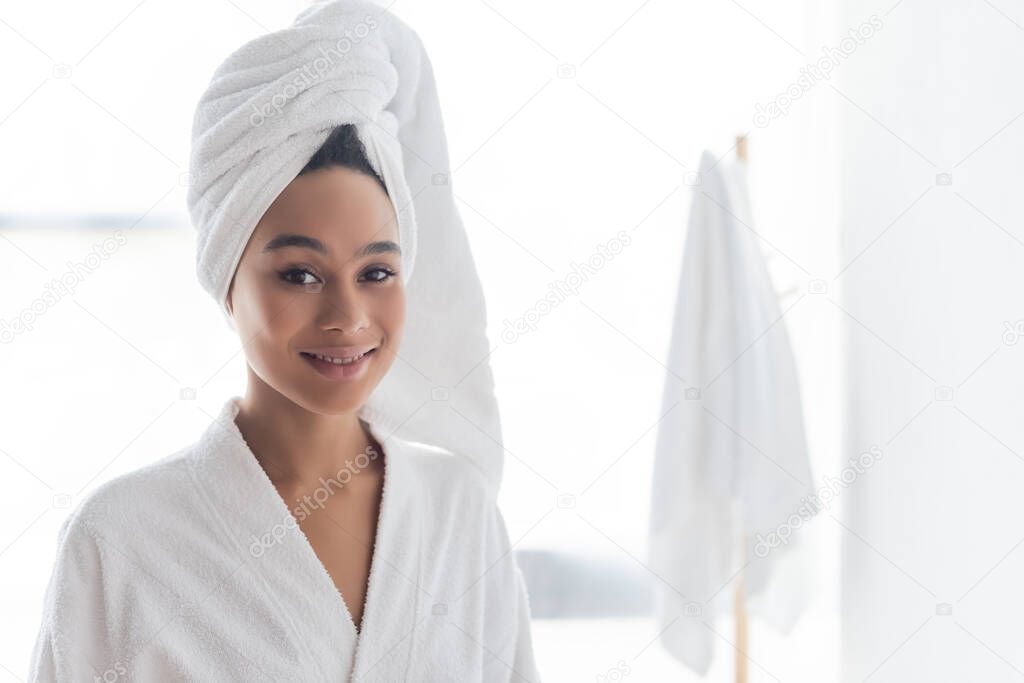 cheerful african american woman in white towel looking at camera