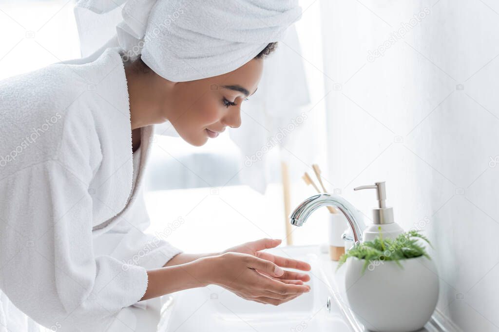 young african american woman washing hands in bathroom