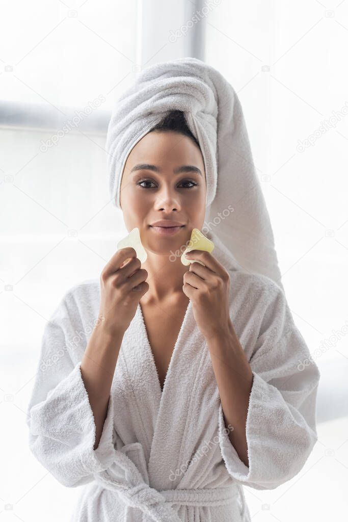 young african american woman in white towel scrapping face with face scrapers